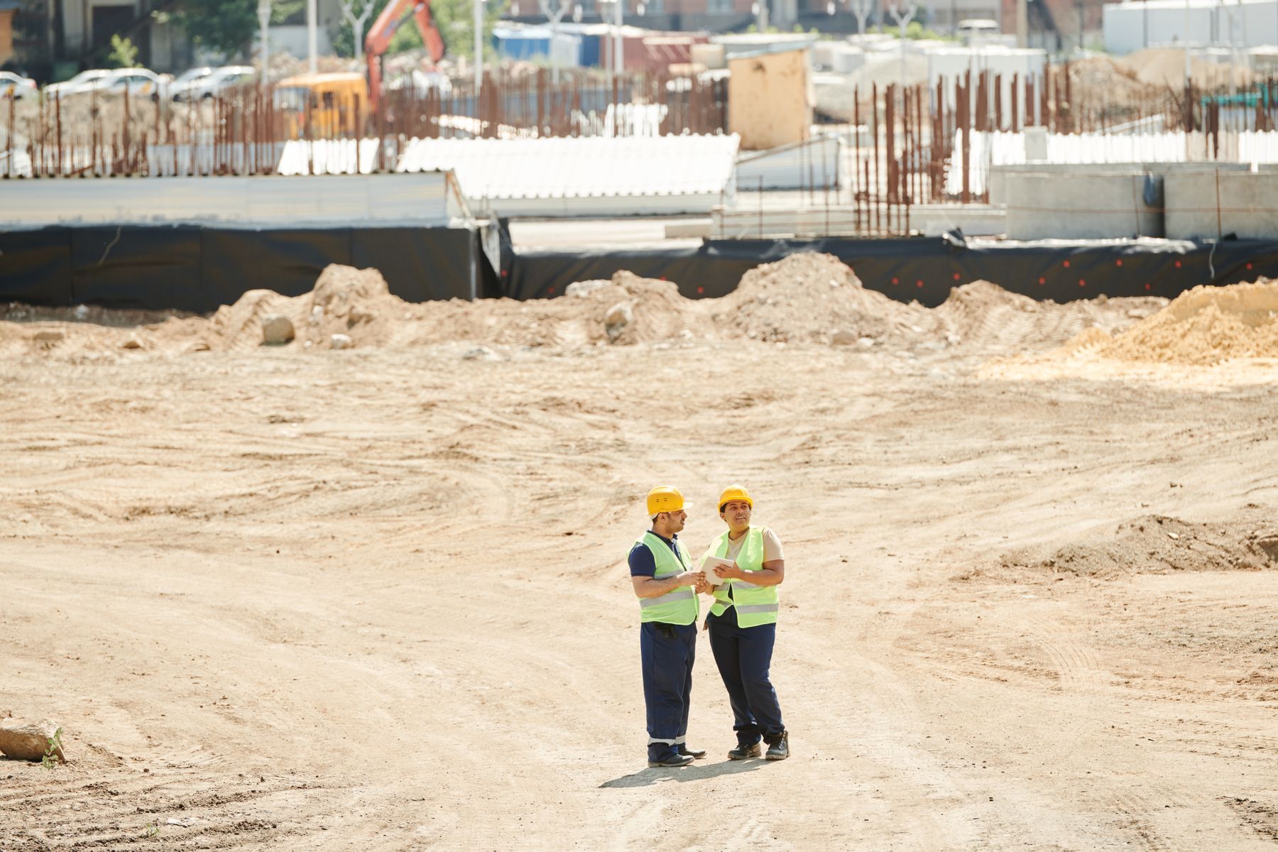 Excavator working on an active construction site with crew in hard hats